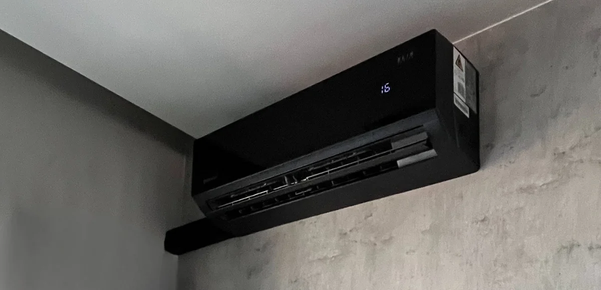Czarna jednostka wewnętrzna klimatyzacji z instalacją prowadzoną w korycie