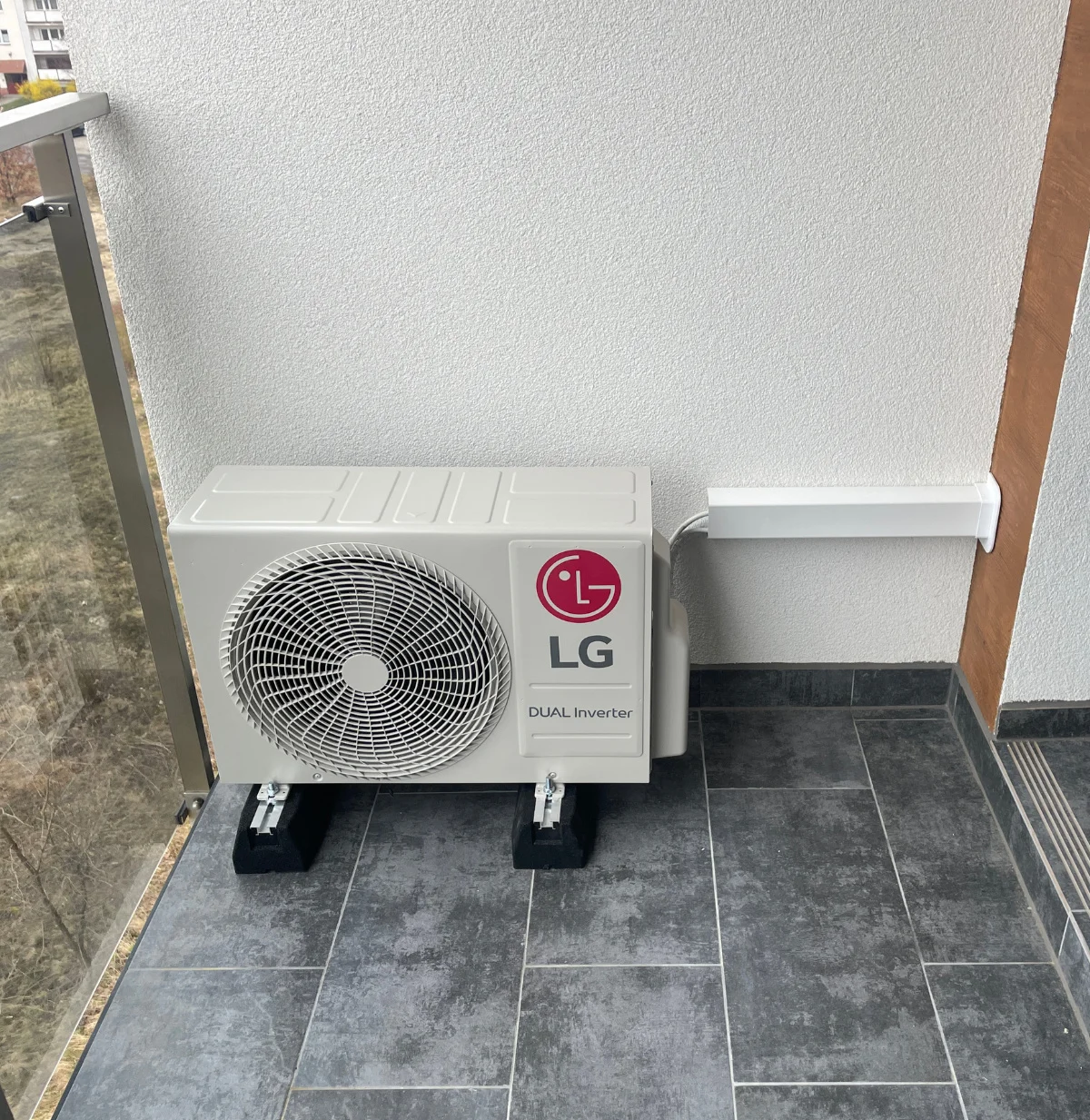 Jednostka zewnętrzna klimatyzacji na balkonie z instalacją w korycie